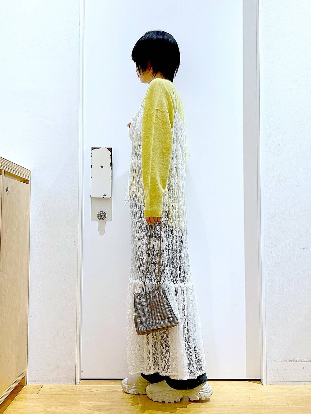 イエロー系のニット/セーター、グレー系のショルダーバッグ、ホワイト系のワンピースを着用したレディースの冬コーディネートの3枚目の写真