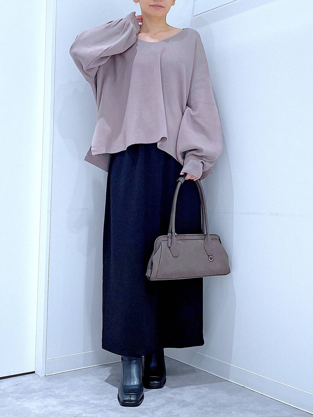 ブラック系のスカート、ブラウン系のニット/セーター、ブラック系のブーツを着用したレディースの秋コーディネートの6枚目の写真