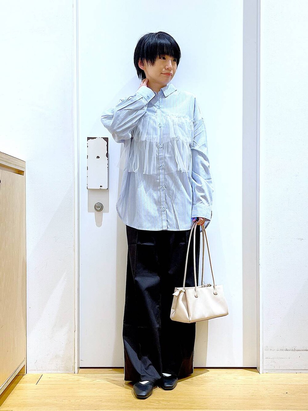 ブラック系のスラックス、ホワイト系のトートバッグ、ブラック系のパンプスを着用したレディースの春コーディネートの2枚目の写真