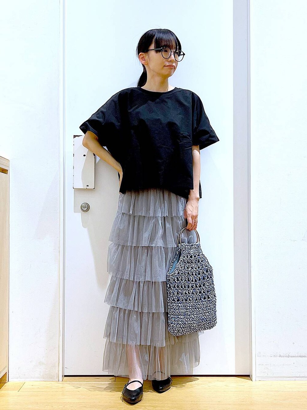 ブラック系のTシャツ/カットソー、ブラック系のパンプス、ブルー系のハンドバッグを着用したレディースの春コーディネートの2枚目の写真