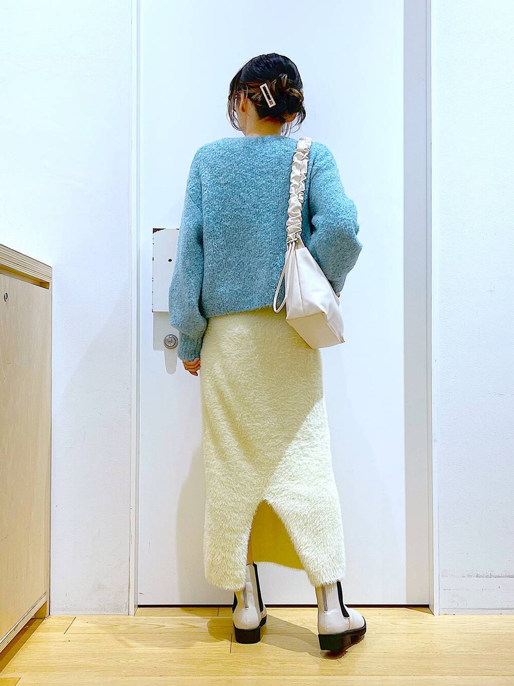 ホワイト系のショルダーバッグ、ベージュ系のブーツ、ホワイト系のスカートを着用したレディースの冬コーディネートの5枚目の写真