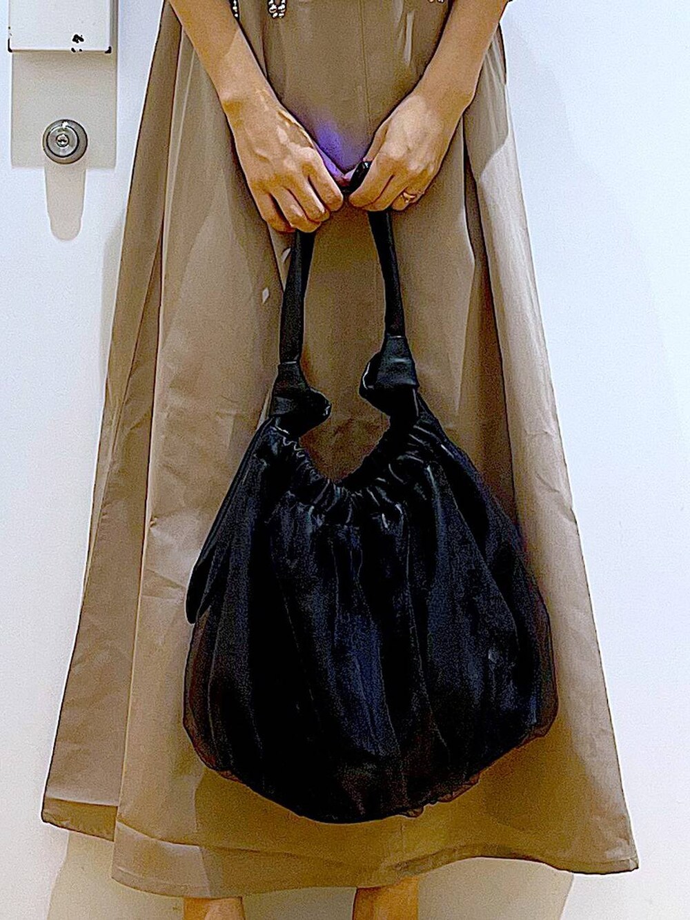 ブラック系のトートバッグ、ベージュ系のワンピース、シルバー系のパンプスを着用したレディースの夏コーディネートの9枚目の写真