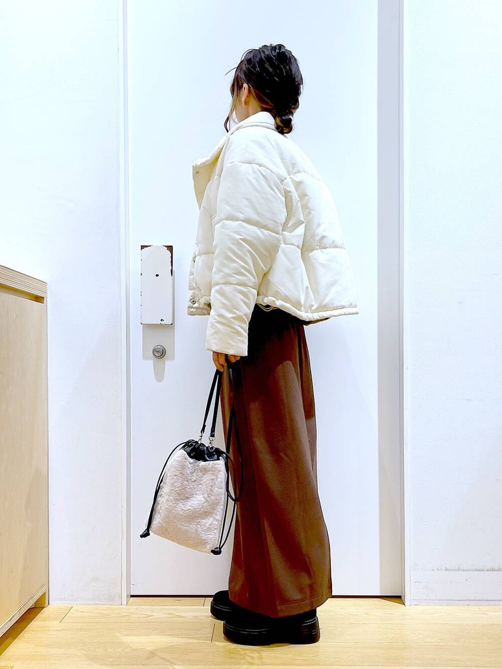 ベージュ系のショルダーバッグ、ブラック系のブーツ、ベージュ系のナイロンジャケットを着用したレディースの冬コーディネートの3枚目の写真