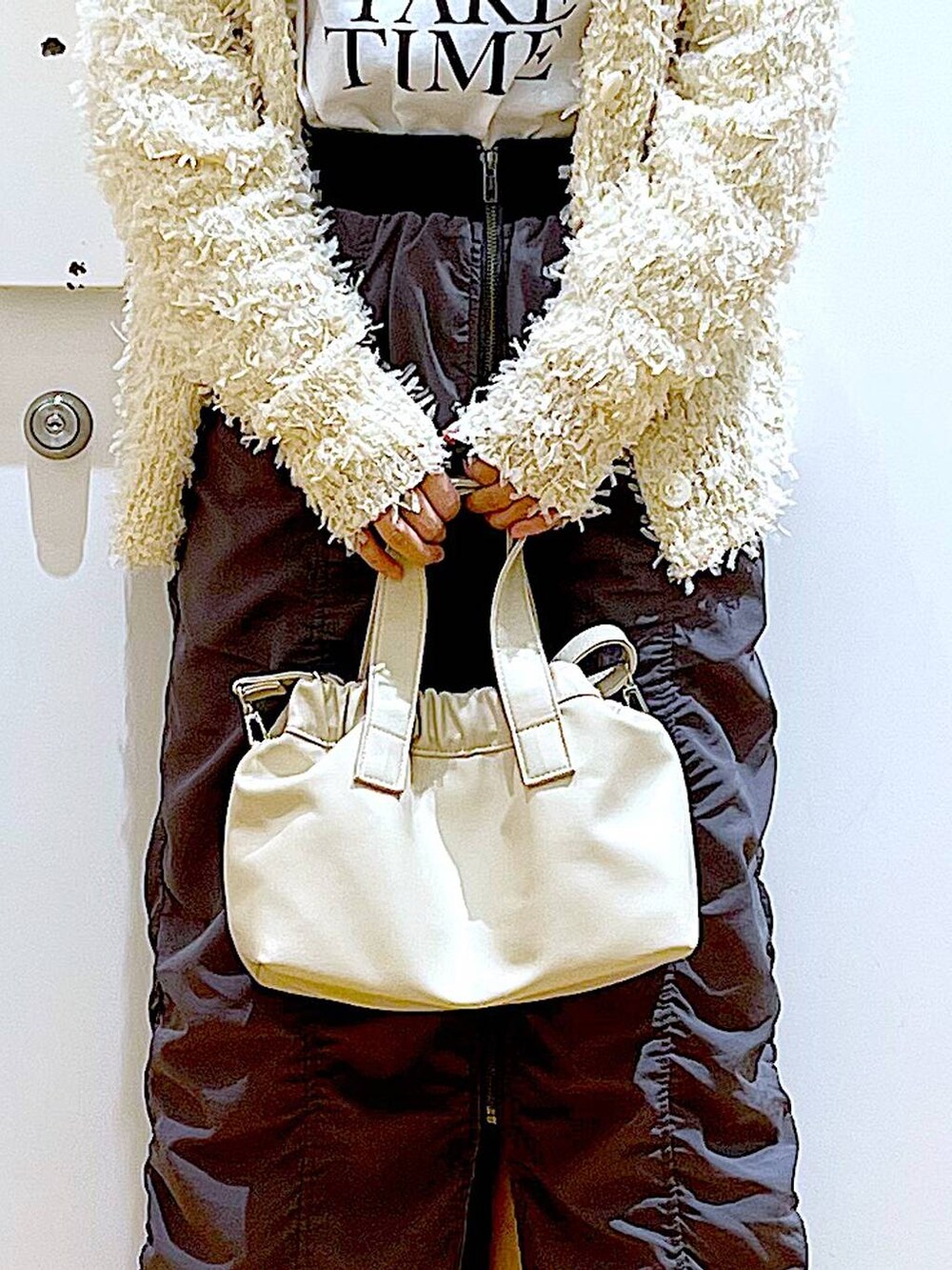 グレー系のスカート、ホワイト系のショルダーバッグ、ホワイト系のパンプスを着用したレディースの春コーディネートの9枚目の写真