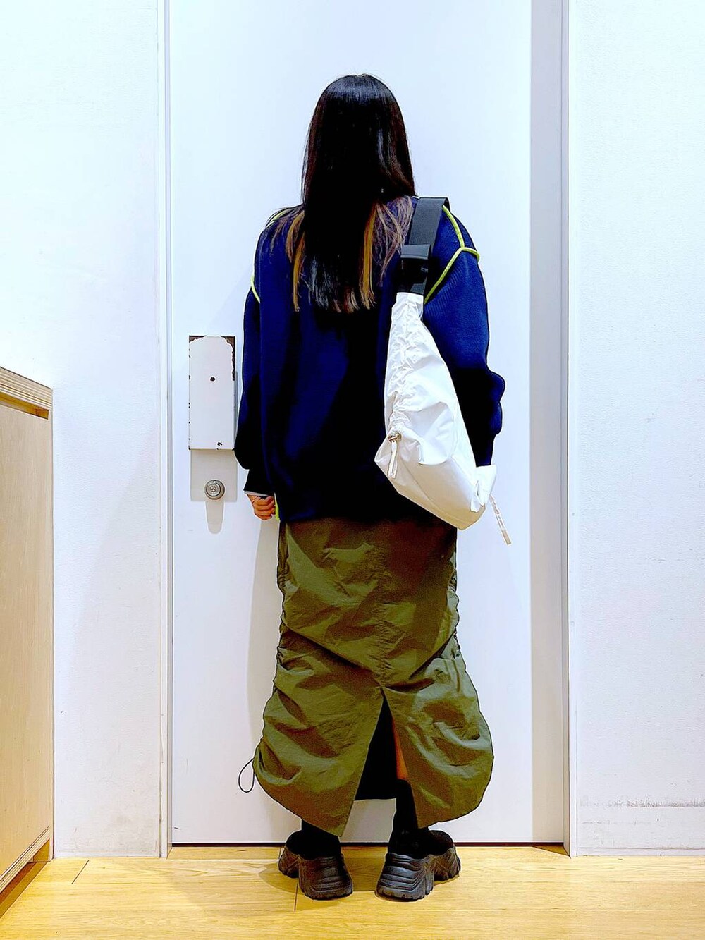 グレー系のスウェット、ブラック系のブーツ、グリーン系のスカートを着用したレディースの冬コーディネートの5枚目の写真