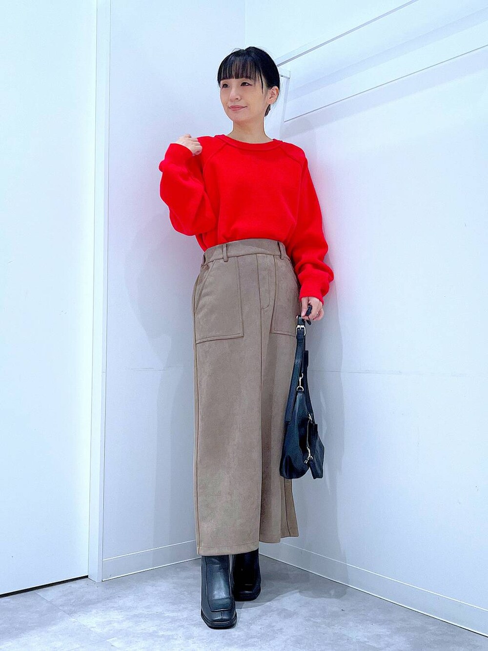 レッド系のニット/セーター、ブラック系のブーツ、ブラック系のショルダーバッグを着用したレディースの冬コーディネートの2枚目の写真