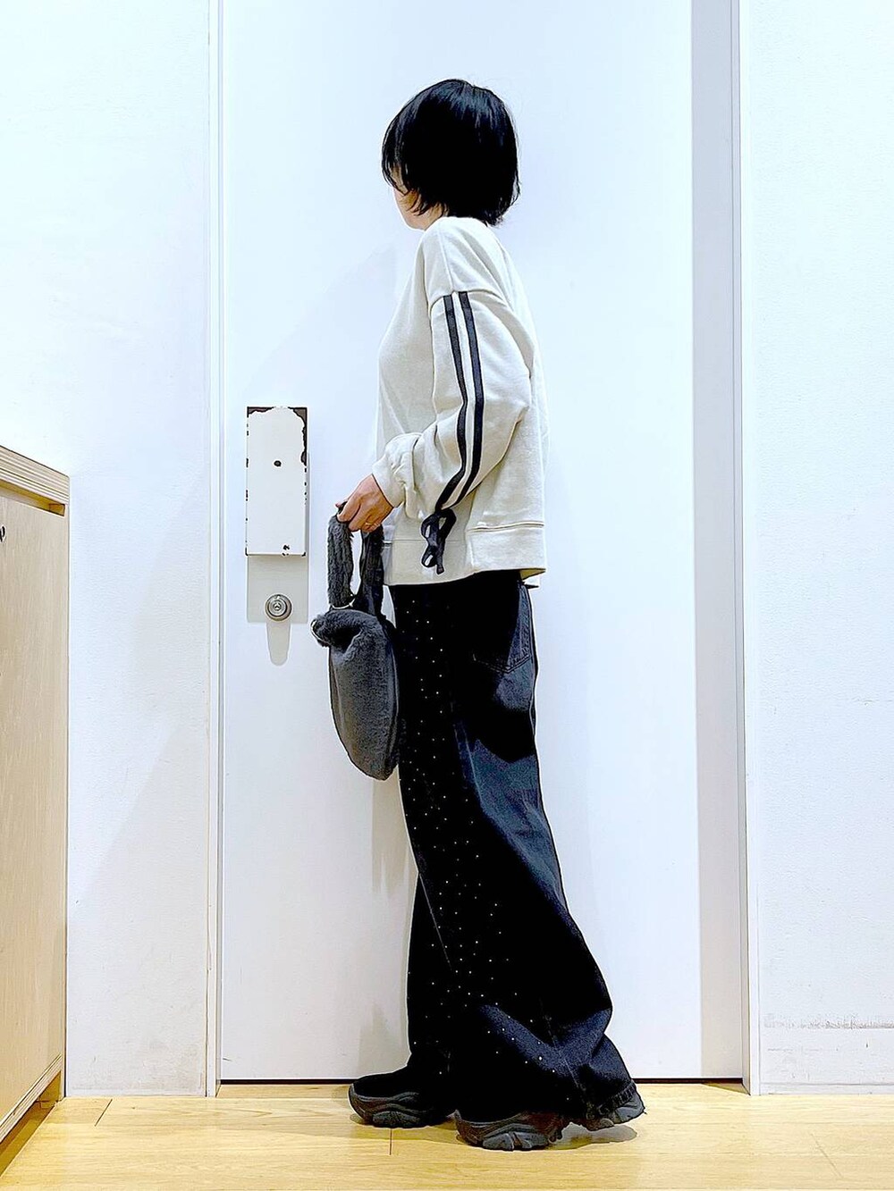 グレー系のショルダーバッグ、ブラック系のブーツ、ベージュ系のスウェットを着用したレディースの秋コーディネートの3枚目の写真