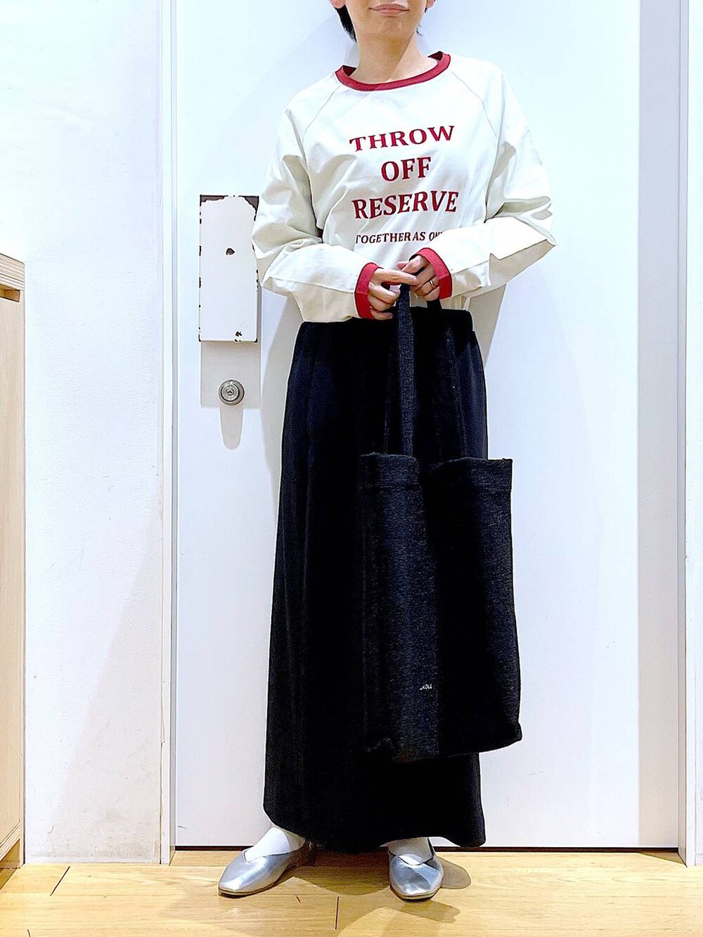 ブラック系のトートバッグ、シルバー系のパンプス、ブラック系のスカートを着用したレディースの春コーディネートの6枚目の写真