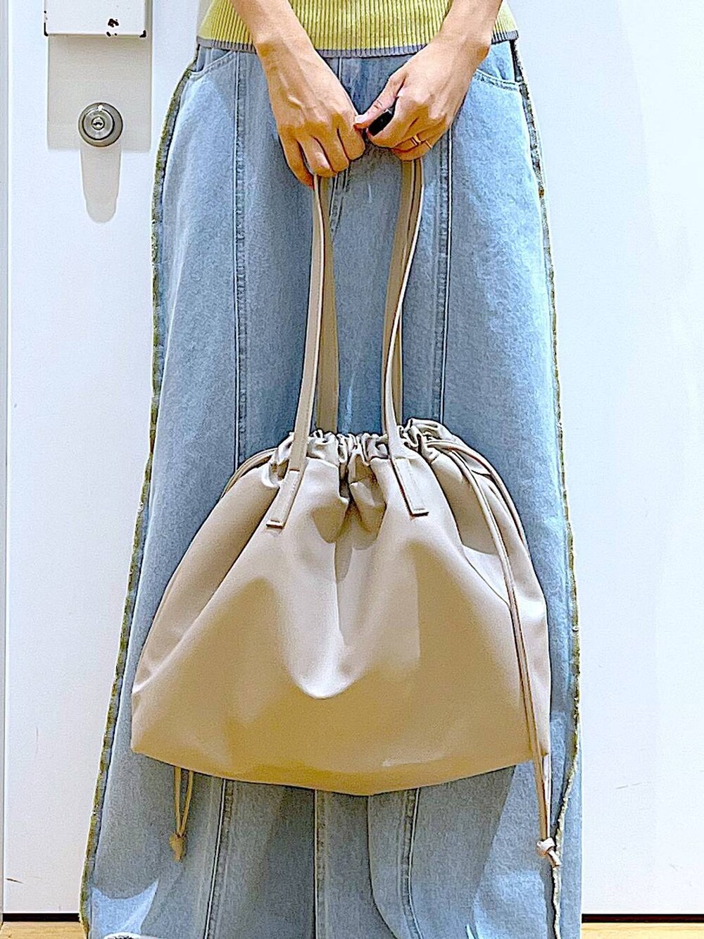 ベージュ系のトートバッグ、シルバー系のローファー、イエロー系のニット/セーターを着用したレディースの秋コーディネートの9枚目の写真