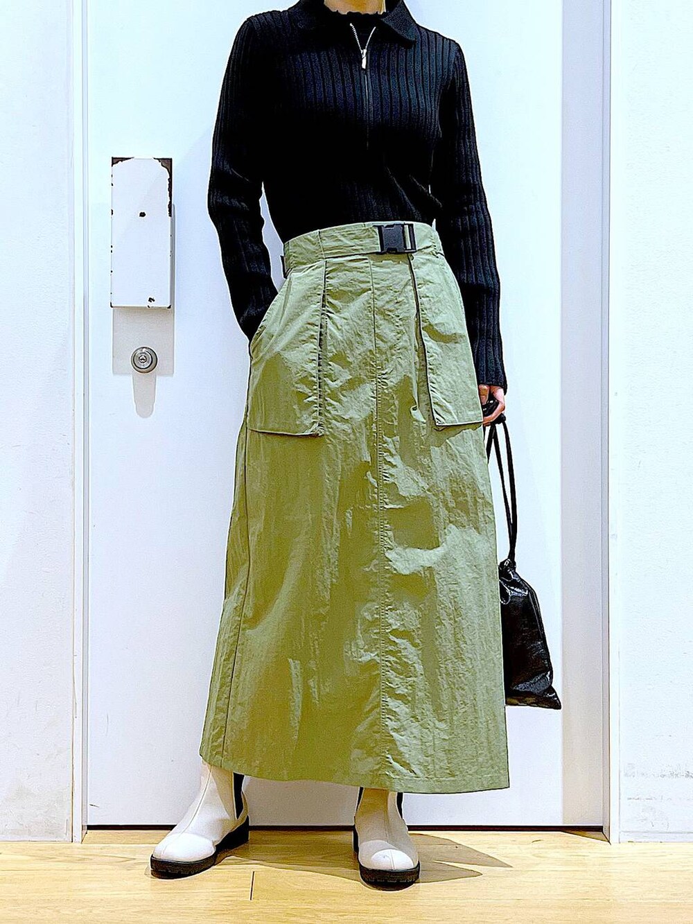 ブラック系のカーディガン/ボレロ、ベージュ系のブーツ、ブラック系のショルダーバッグを着用したレディースの春コーディネートの6枚目の写真