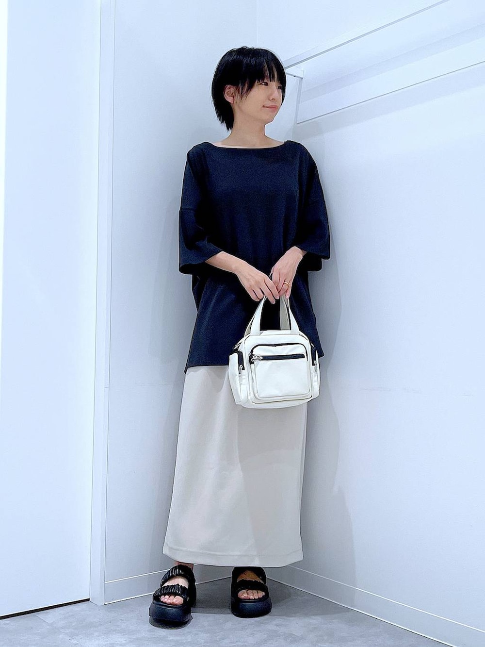 ブラック系のサンダル、ベージュ系のスカート、ホワイト系のショルダーバッグを着用したレディースの夏コーディネートの2枚目の写真