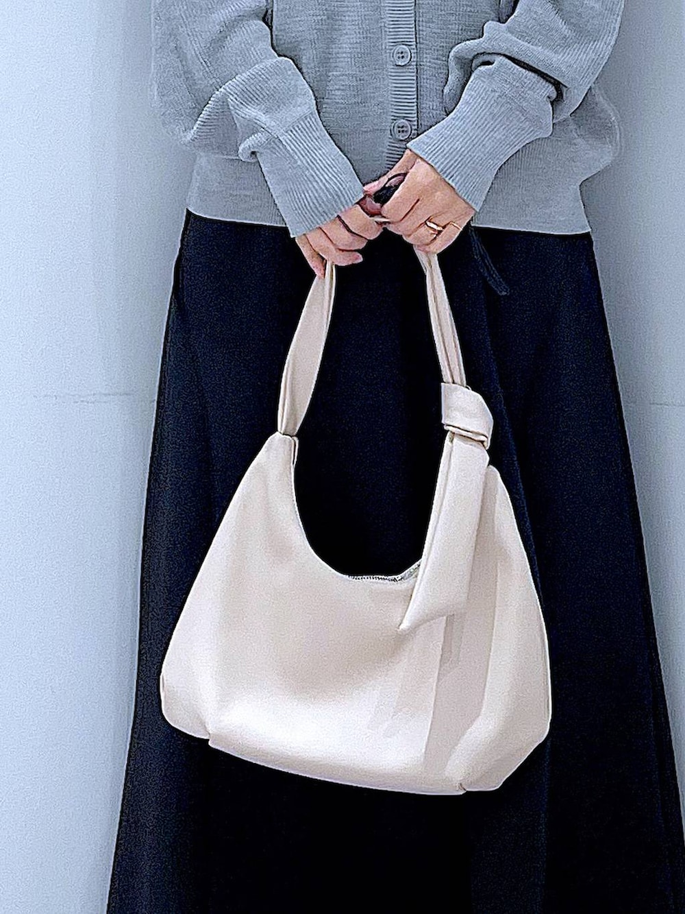 ホワイト系のショルダーバッグ、ブラック系のスカート、グレー系のカーディガン/ボレロを着用したレディースの春コーディネートの9枚目の写真