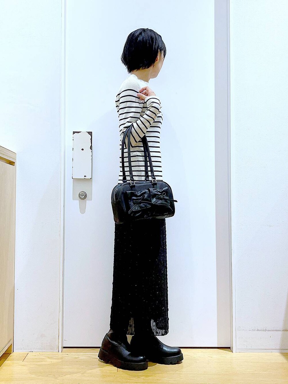 ホワイト系のニット/セーター、ブラック系のハンドバッグ、ブラック系のブーツを着用したレディースの秋コーディネートの4枚目の写真