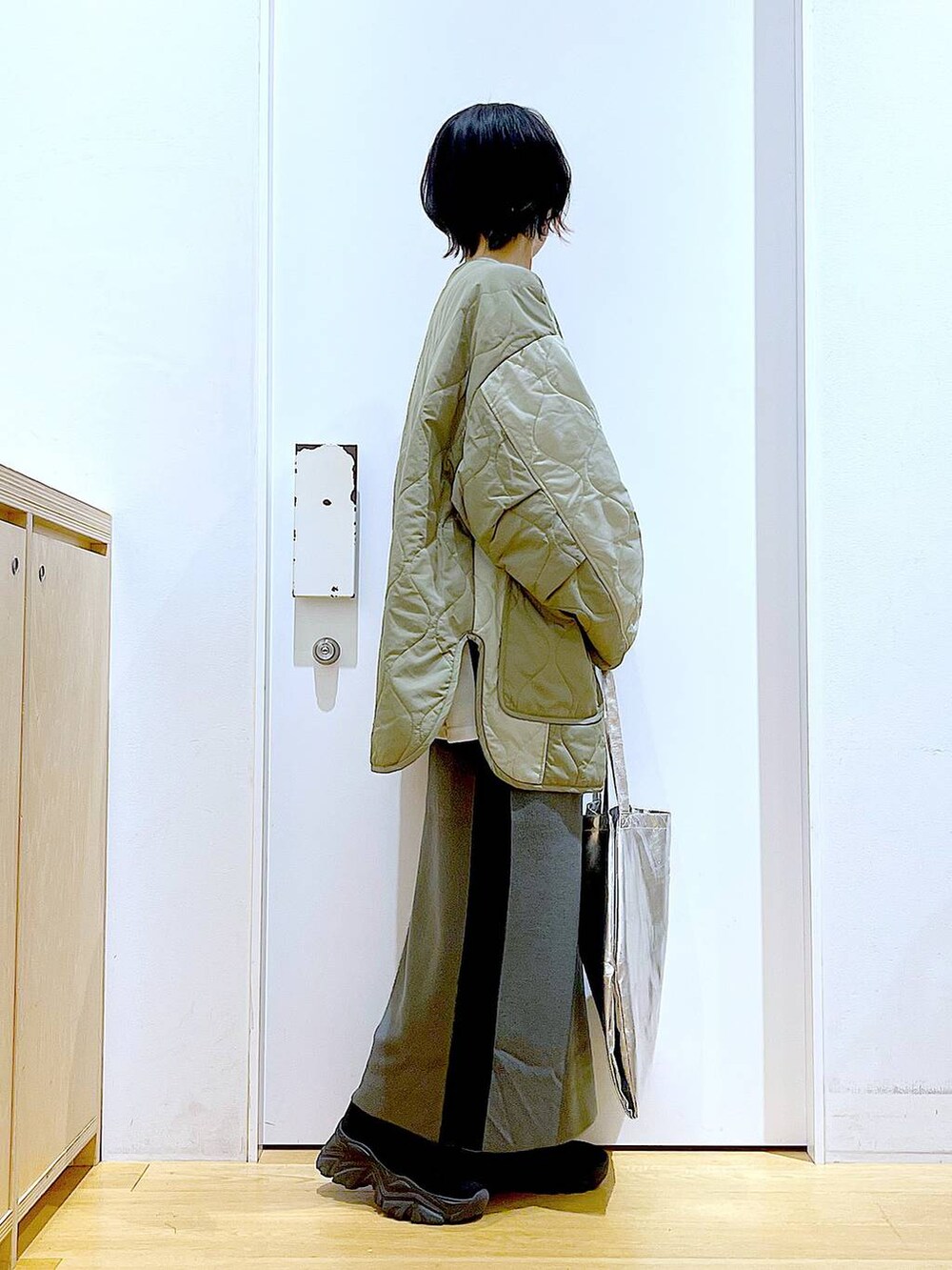 シルバー系のトートバッグ、グレー系のスカート、ブラック系のブーツを着用したレディースの秋コーディネートの4枚目の写真