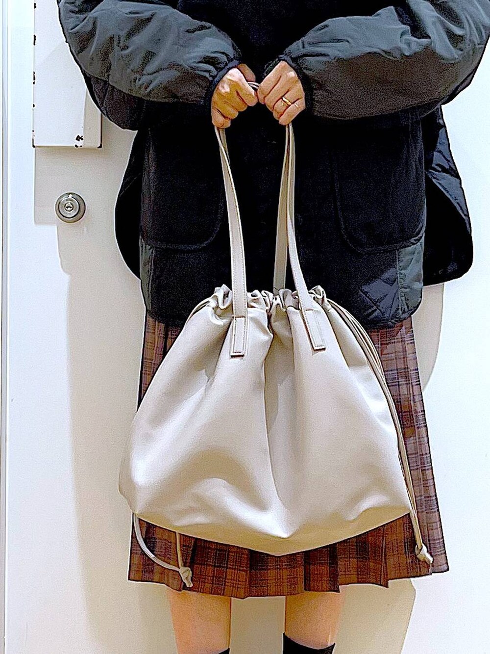 ベージュ系のトートバッグ、ブラック系のブルゾン、ブラック系のTシャツ/カットソーを着用したレディースの秋コーディネートの9枚目の写真