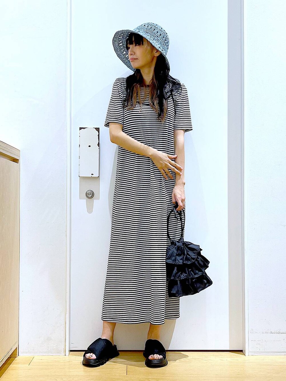 ブラック系のショルダーバッグ、ブラック系のサンダル、ブラック系のワンピースを着用したレディースの夏コーディネートの2枚目の写真