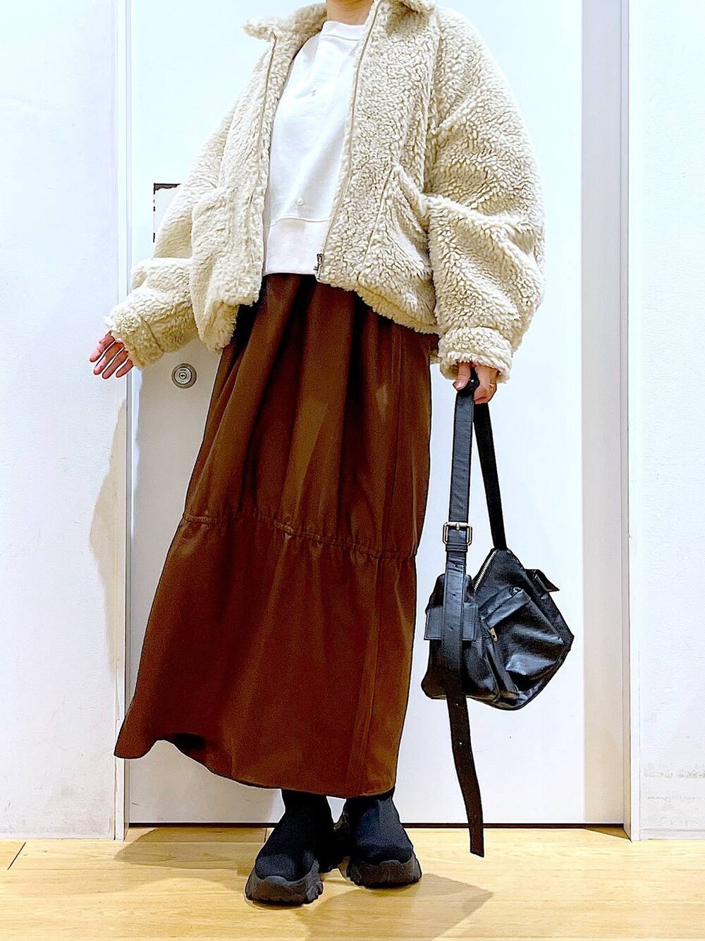 ホワイト系のブルゾン、ホワイト系のスウェット、ブラック系のブーツを着用したレディースの冬コーディネートの6枚目の写真