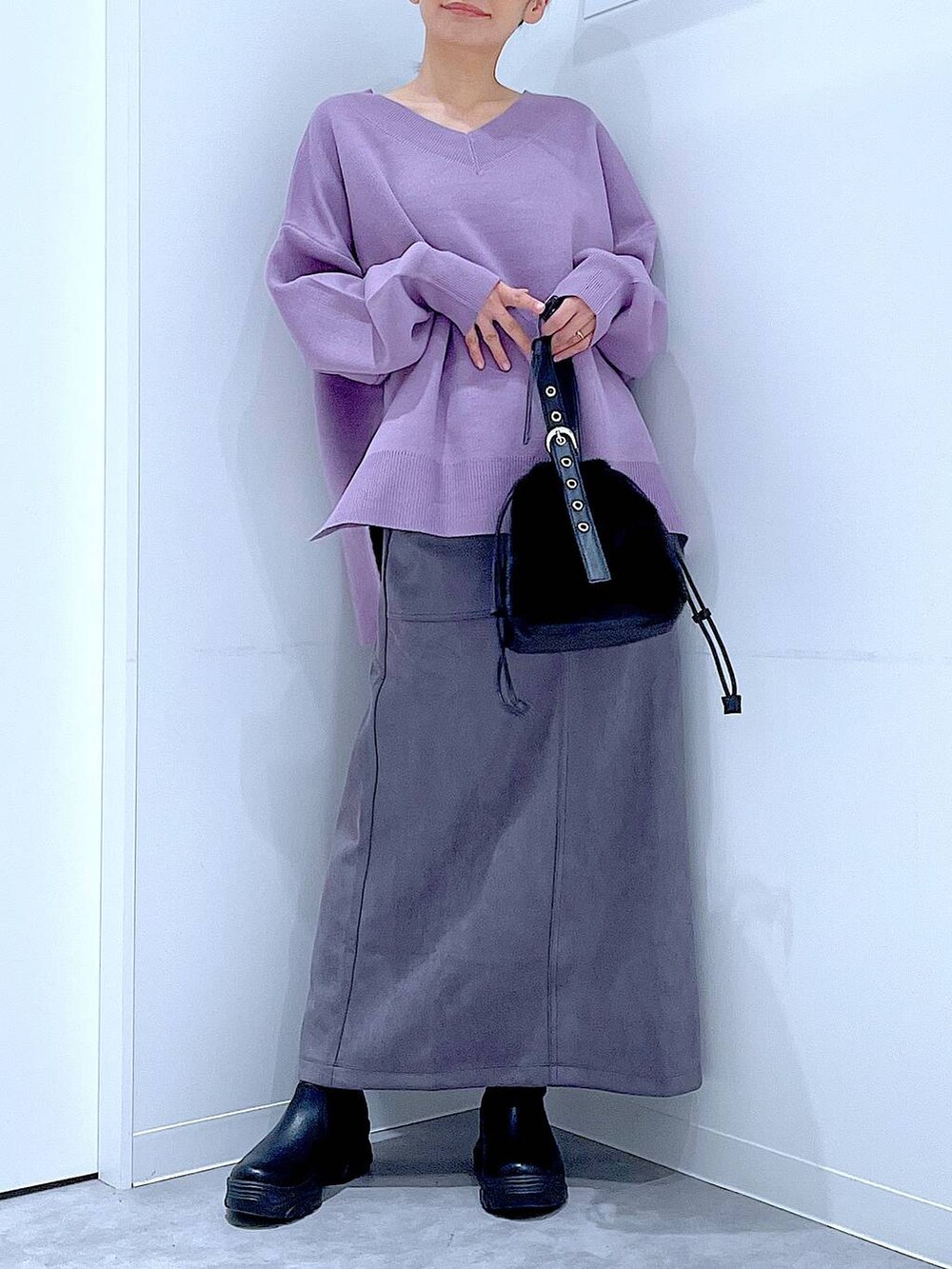 ブラック系のハンドバッグ、ブラック系のブーツ、グレー系のスカートを着用したレディースの冬コーディネートの6枚目の写真