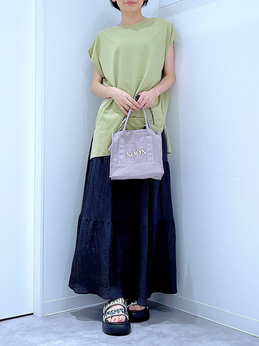 シルバー系のサンダル、グリーン系のTシャツ/カットソー、ブラック系のスカートを着用したレディースの夏コーディネートの6枚目の写真