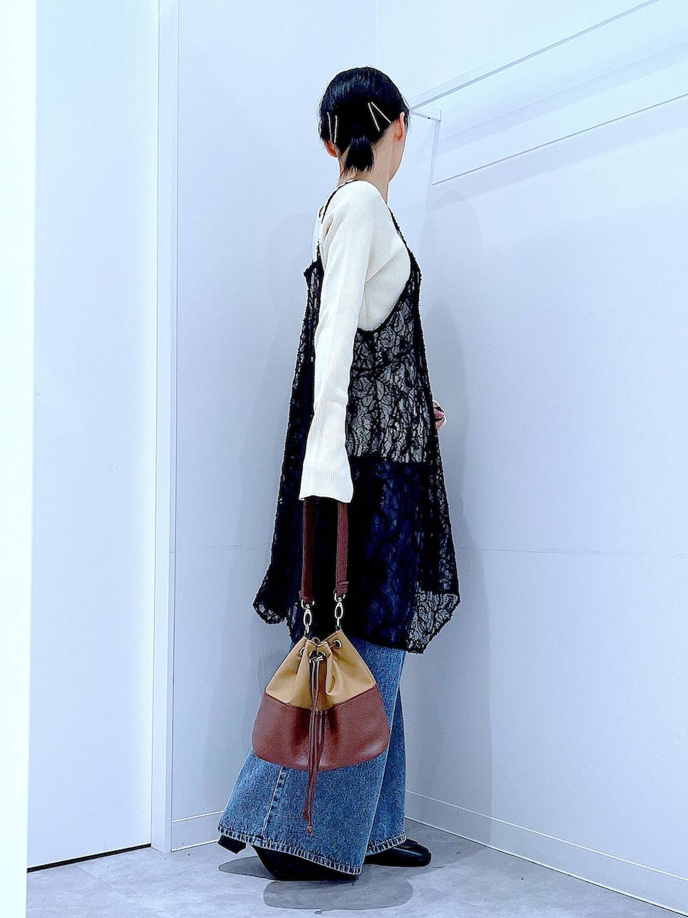 ベージュ系のニット/セーター、ブルー系のデニムパンツ、ベージュ系のショルダーバッグを着用したレディースの秋コーディネートの4枚目の写真