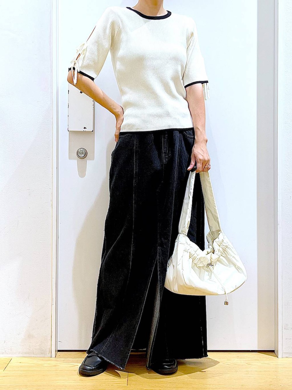 ホワイト系のハンドバッグ、ブラック系のローファー、ホワイト系のニット/セーターを着用したレディースの秋コーディネートの6枚目の写真