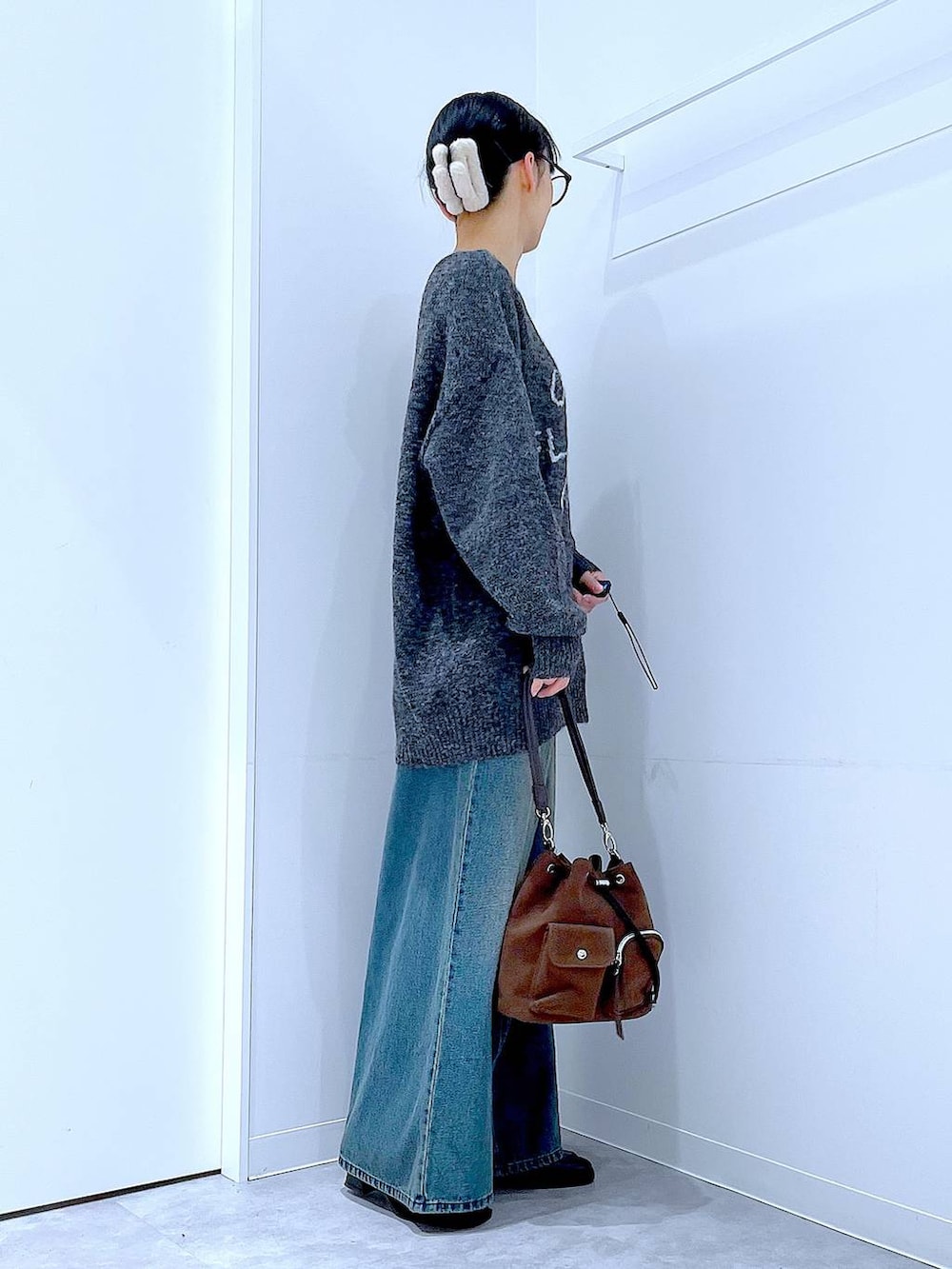 ブラウン系のショルダーバッグ、ブルー系のデニムパンツ、ブラック系のブーツを着用したレディースの冬コーディネートの4枚目の写真