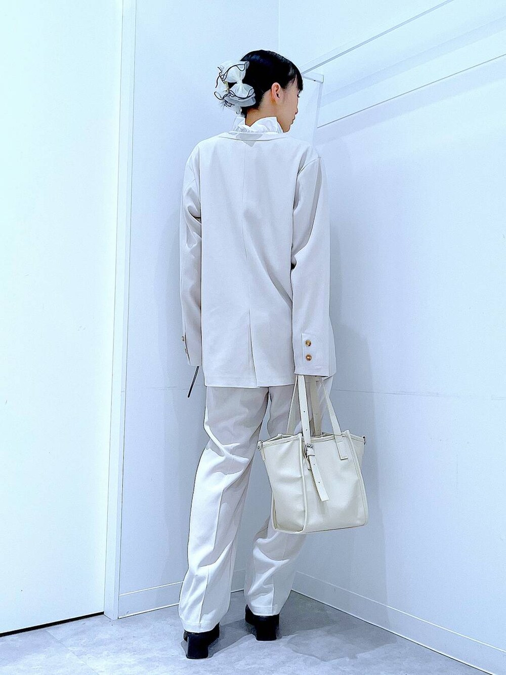 ブラック系のブーツ、ホワイト系のトートバッグ、ベージュ系のノーカラージャケットを着用したレディースの冬コーディネートの5枚目の写真