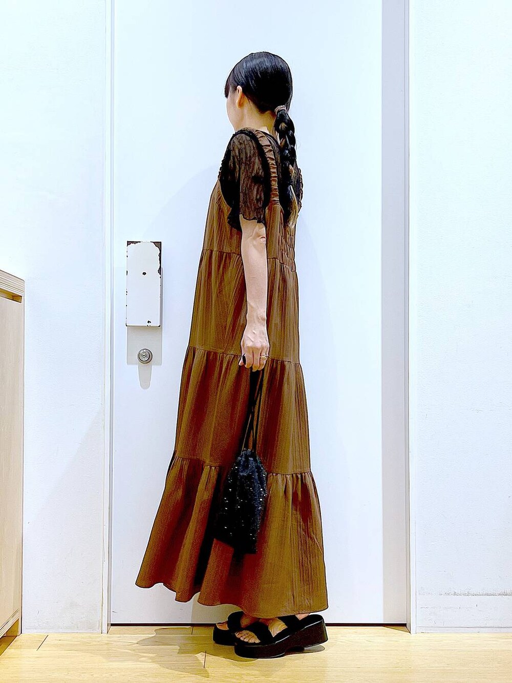 ブラック系のサンダル、ブラック系のショルダーバッグ、ベージュ系のワンピースを着用したレディースの夏コーディネートの3枚目の写真