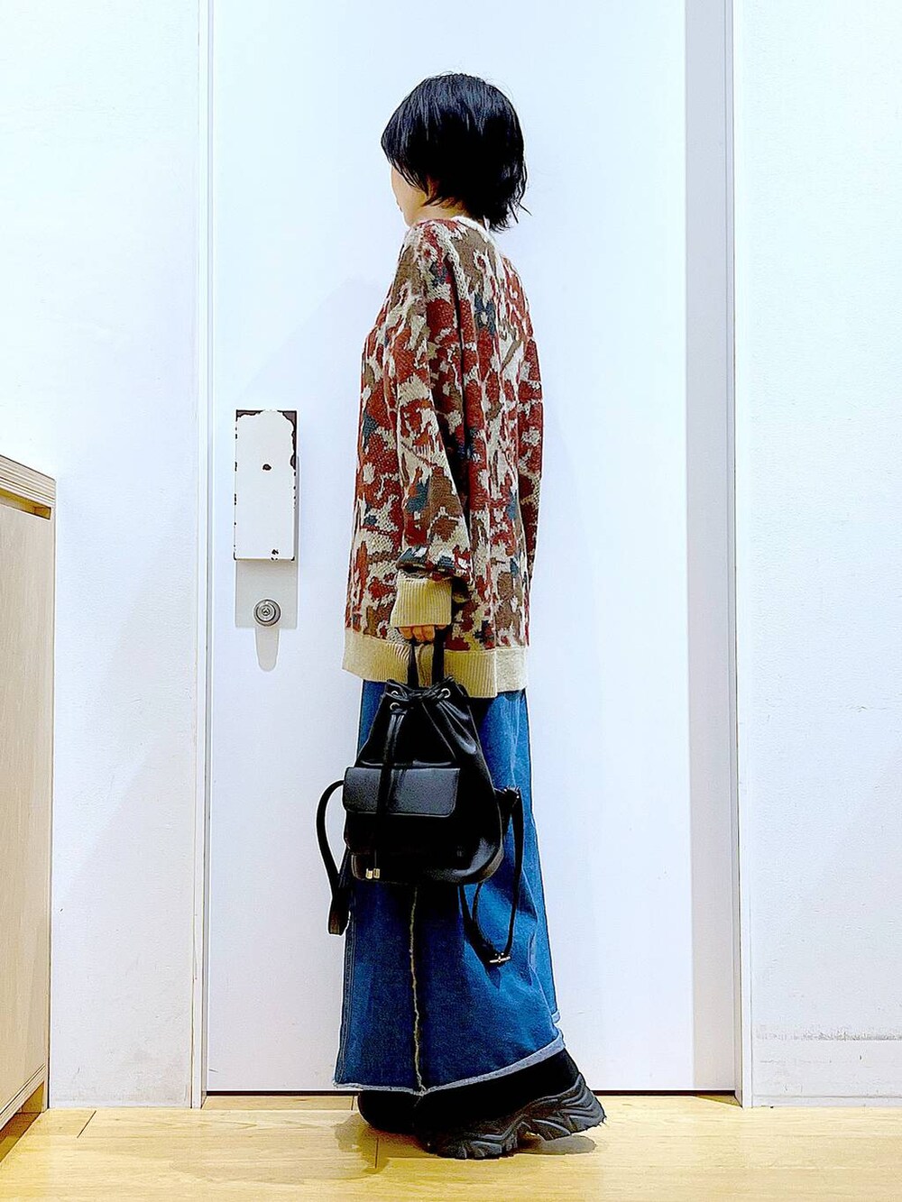 ブラック系のバックパック/リュック、ブルー系のデニムスカート、ブラック系のブーツを着用したレディースの冬コーディネートの3枚目の写真