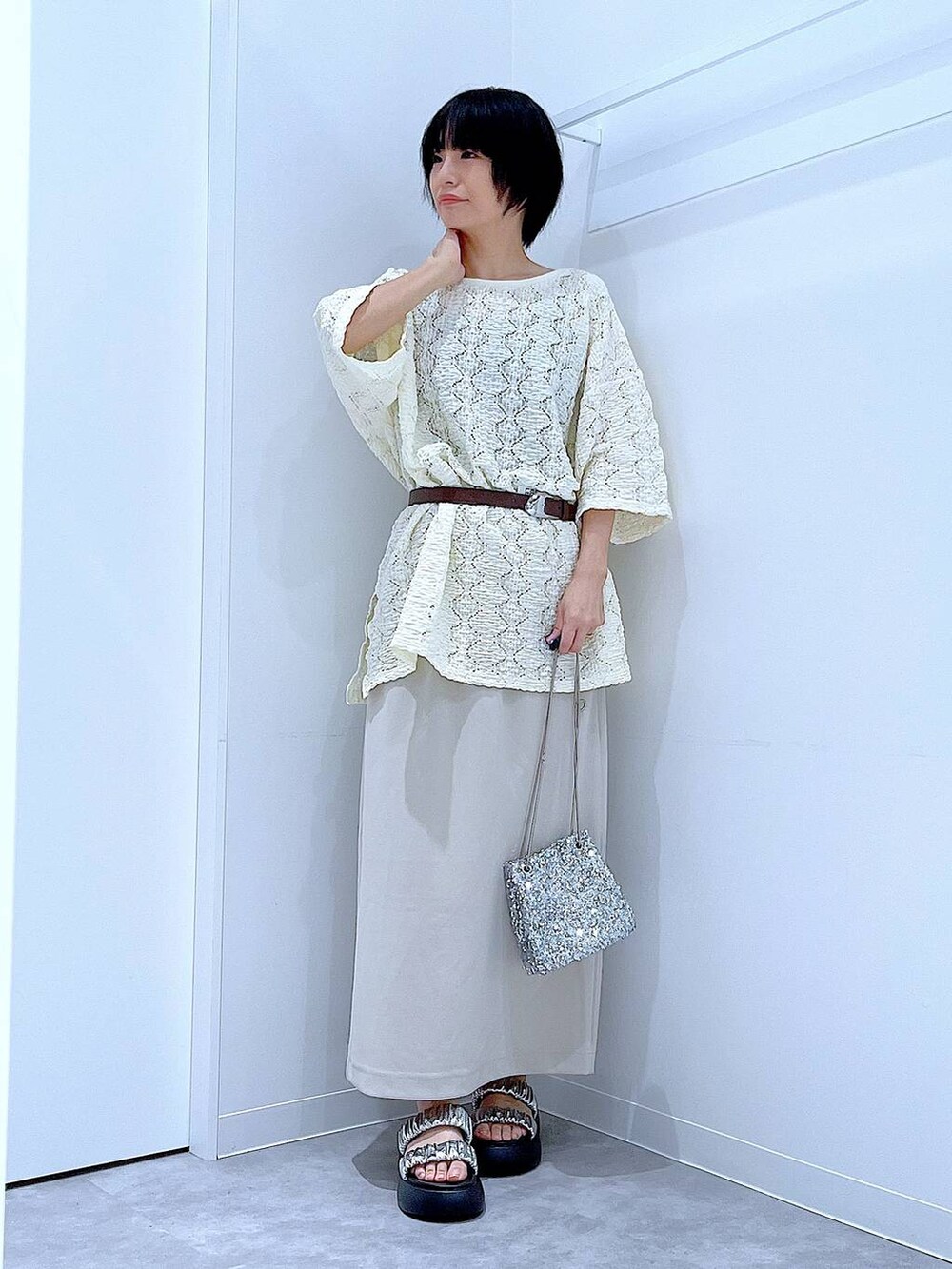 シルバー系のサンダル、ベージュ系のスカート、シルバー系のショルダーバッグを着用したレディースの夏コーディネートの2枚目の写真