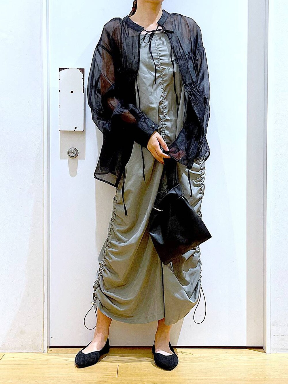 ブラック系のショルダーバッグ、ブラック系のパンプス、グリーン系のワンピースを着用したレディースの春コーディネートの6枚目の写真