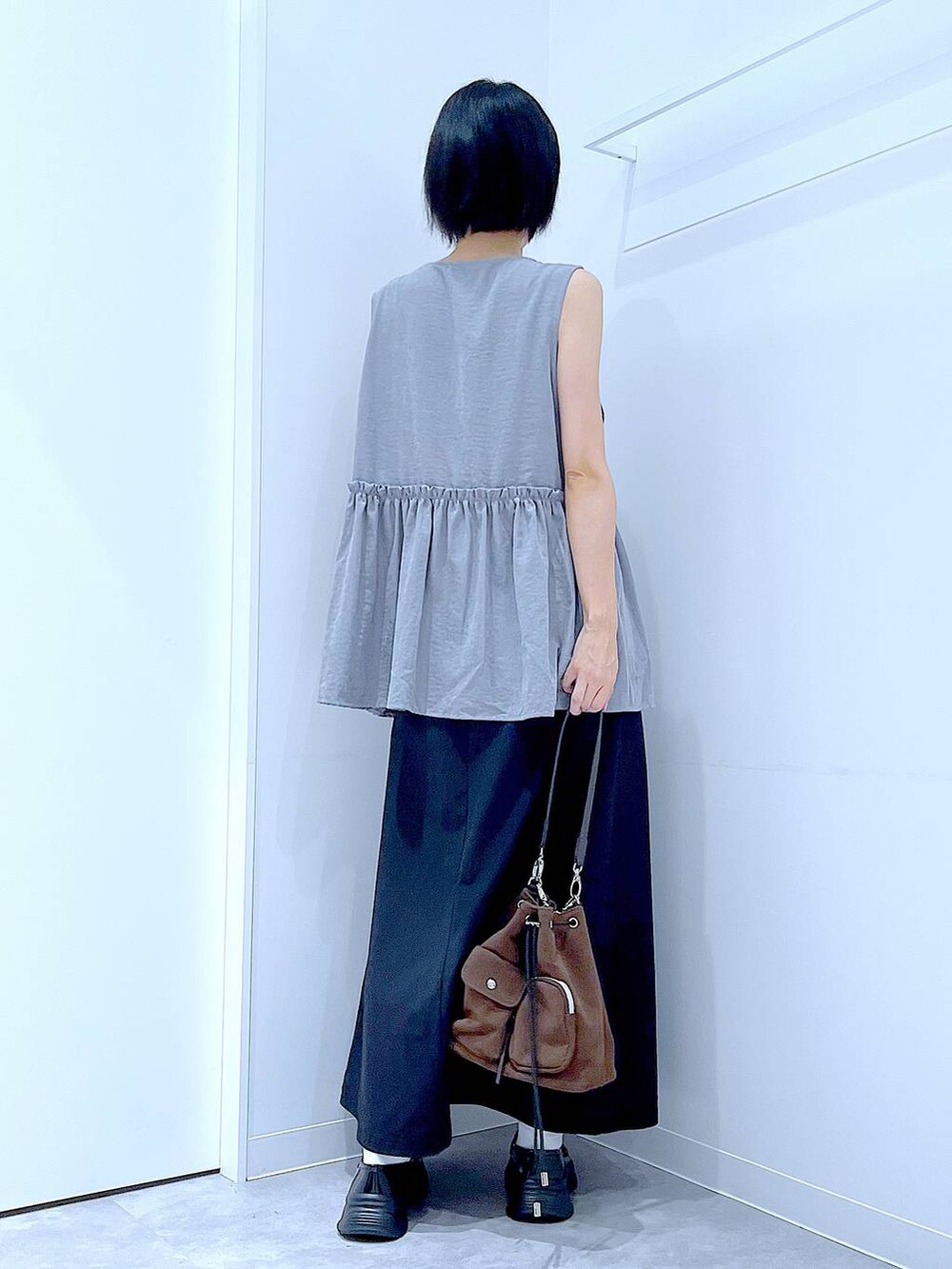 ブラック系のスカート、ブラック系のローファー、ブラウン系のショルダーバッグを着用したレディースの秋コーディネートの5枚目の写真