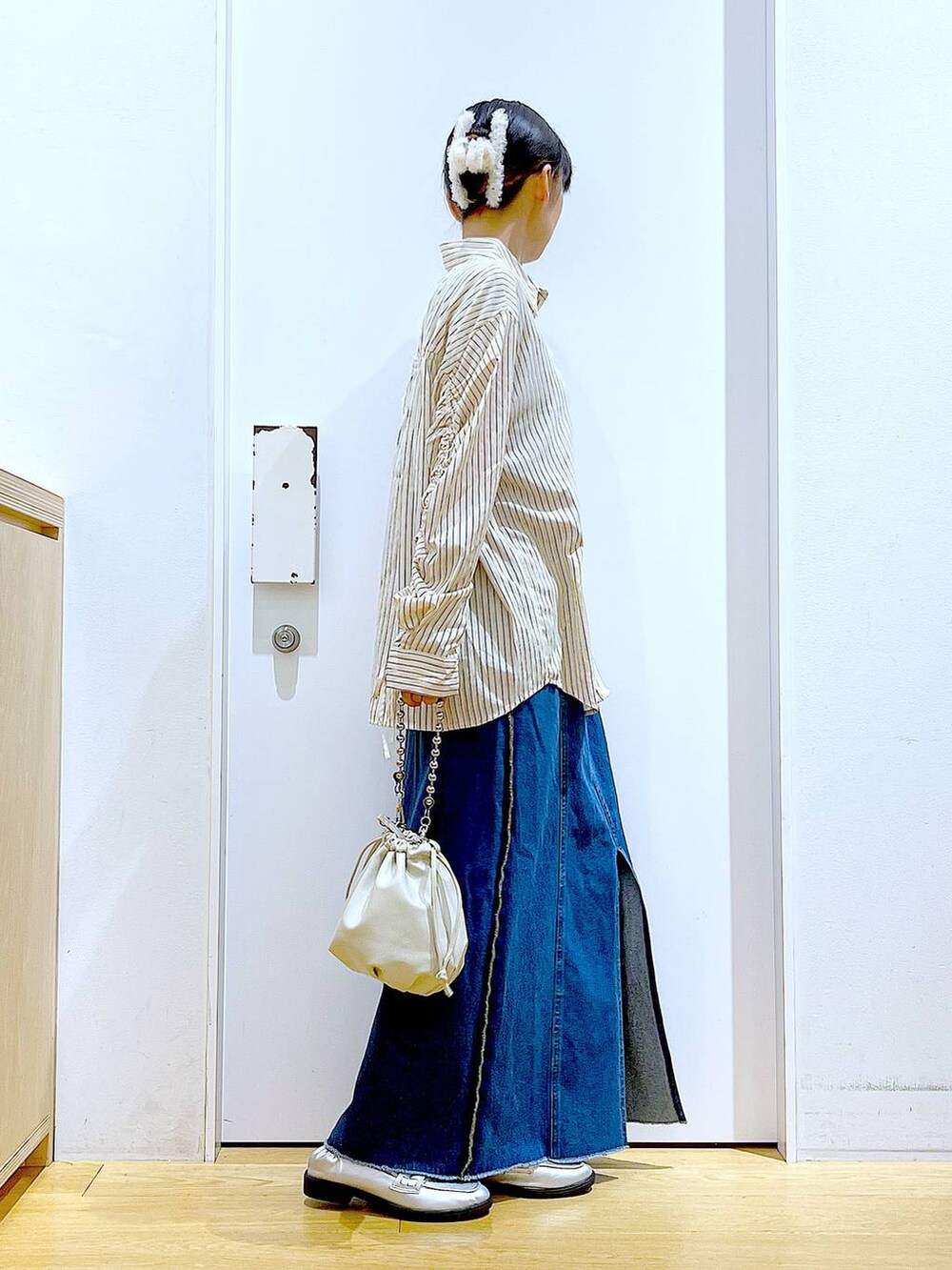 ベージュ系のショルダーバッグ、シルバー系のローファー、ブルー系のデニムスカートを着用したレディースの秋コーディネートの4枚目の写真