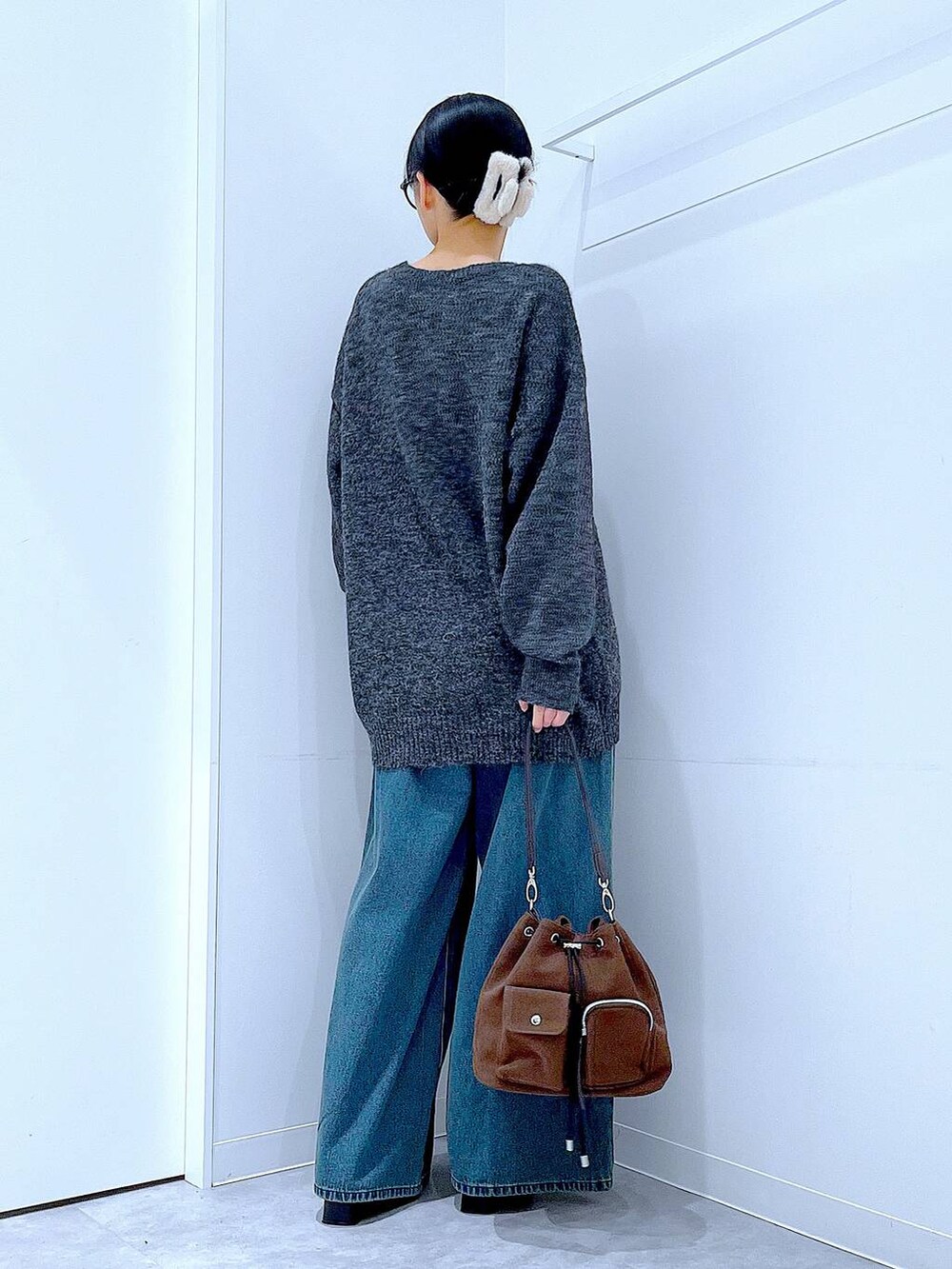 ブラウン系のショルダーバッグ、ブルー系のデニムパンツ、ブラック系のブーツを着用したレディースの冬コーディネートの5枚目の写真