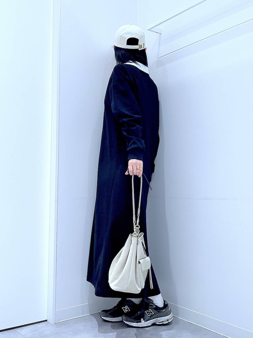 ホワイト系のショルダーバッグ、ブラック系のワンピース、ホワイト系のキャップを着用したレディースの春コーディネートの3枚目の写真