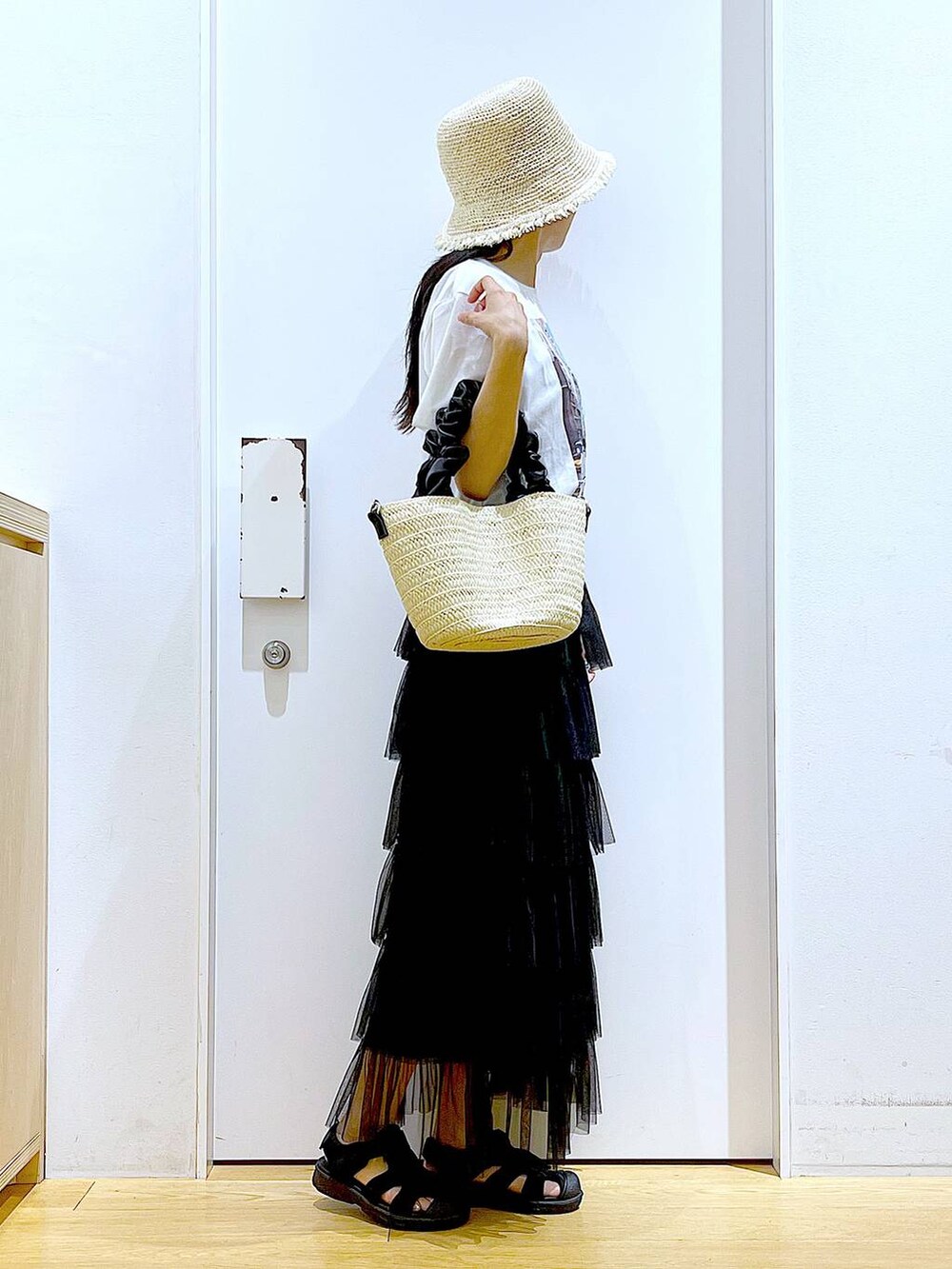 ホワイト系のショルダーバッグ、ブラック系のスリッポン、ブラック系のスカートを着用したレディースの夏コーディネートの4枚目の写真