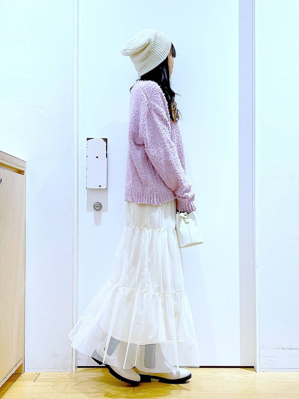 パープル系のニット/セーター、ベージュ系のブーツ、ホワイト系のショルダーバッグを着用したレディースの春コーディネートの4枚目の写真