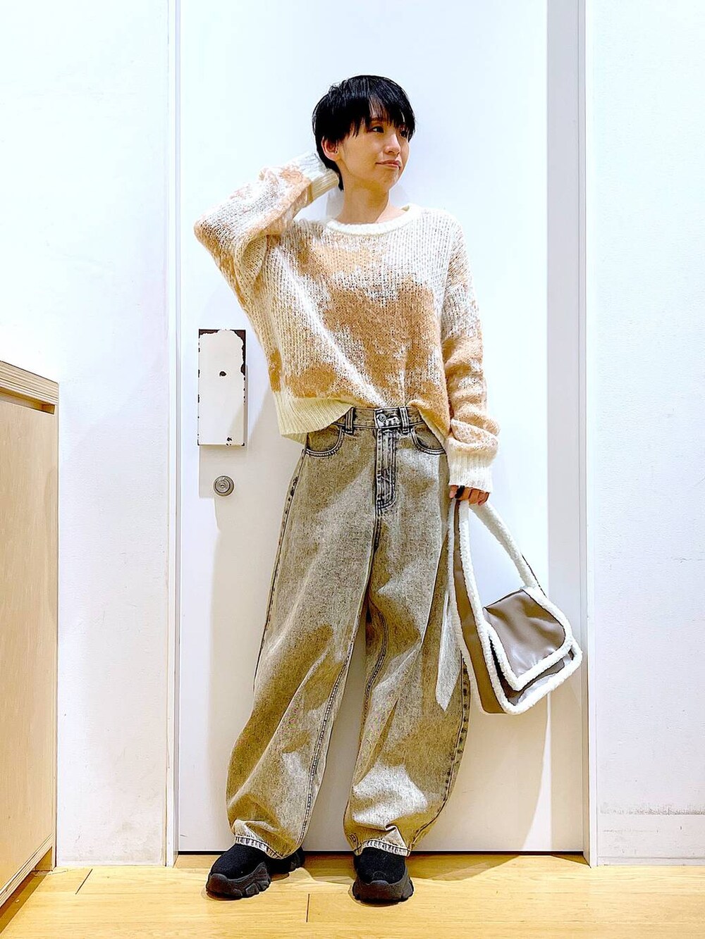 ブラック系のブーツ、ベージュ系のショルダーバッグ、ベージュ系のデニムパンツを着用したレディースの冬コーディネートの2枚目の写真