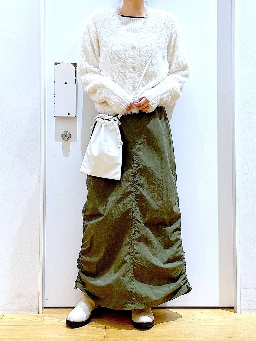 ベージュ系のブーツ、ベージュ系のニット/セーター、グリーン系のスカートを着用したレディースの冬コーディネートの6枚目の写真