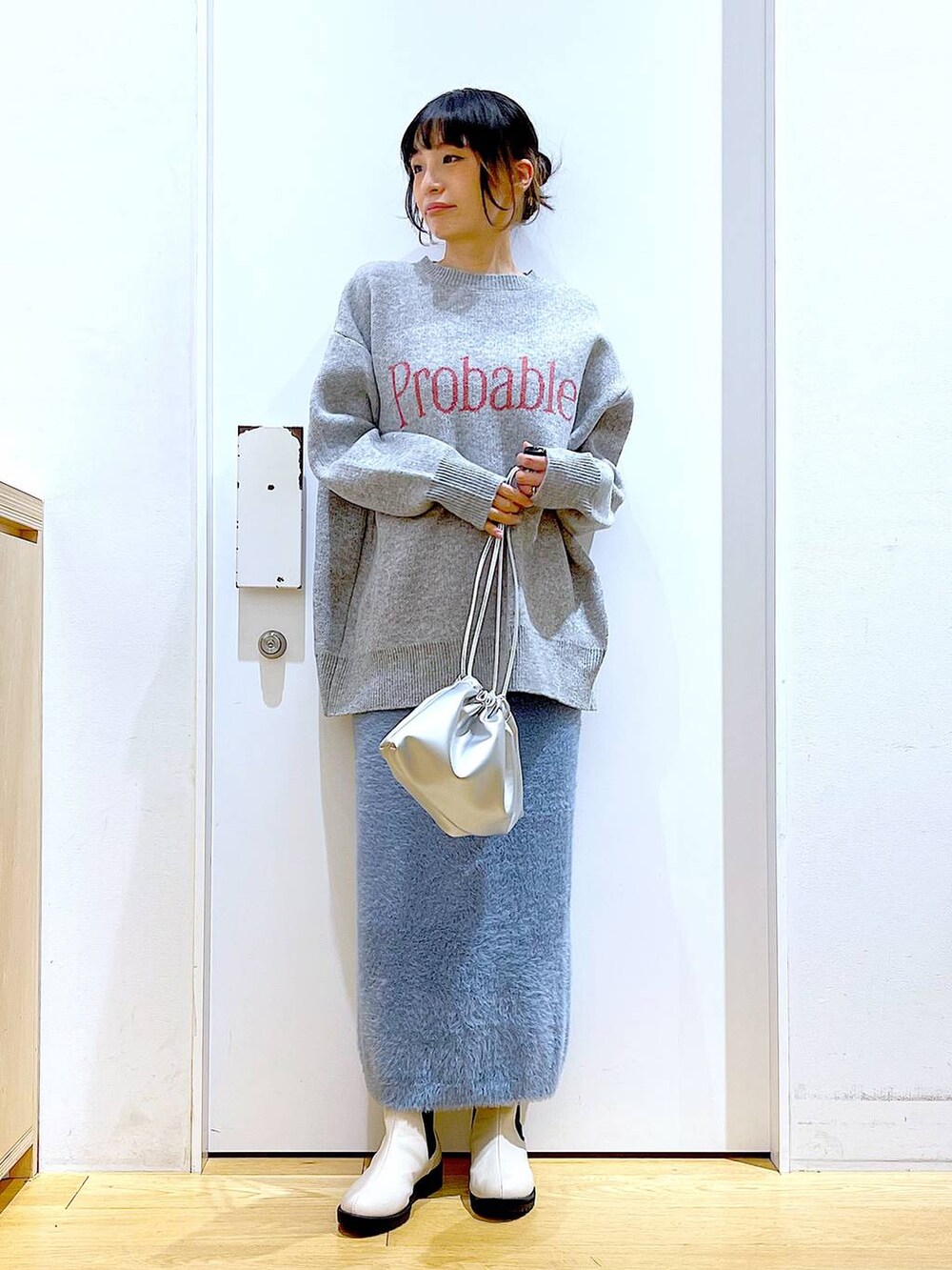 ベージュ系のブーツ、シルバー系のショルダーバッグ、ブルー系のスカートを着用したレディースの冬コーディネートの2枚目の写真