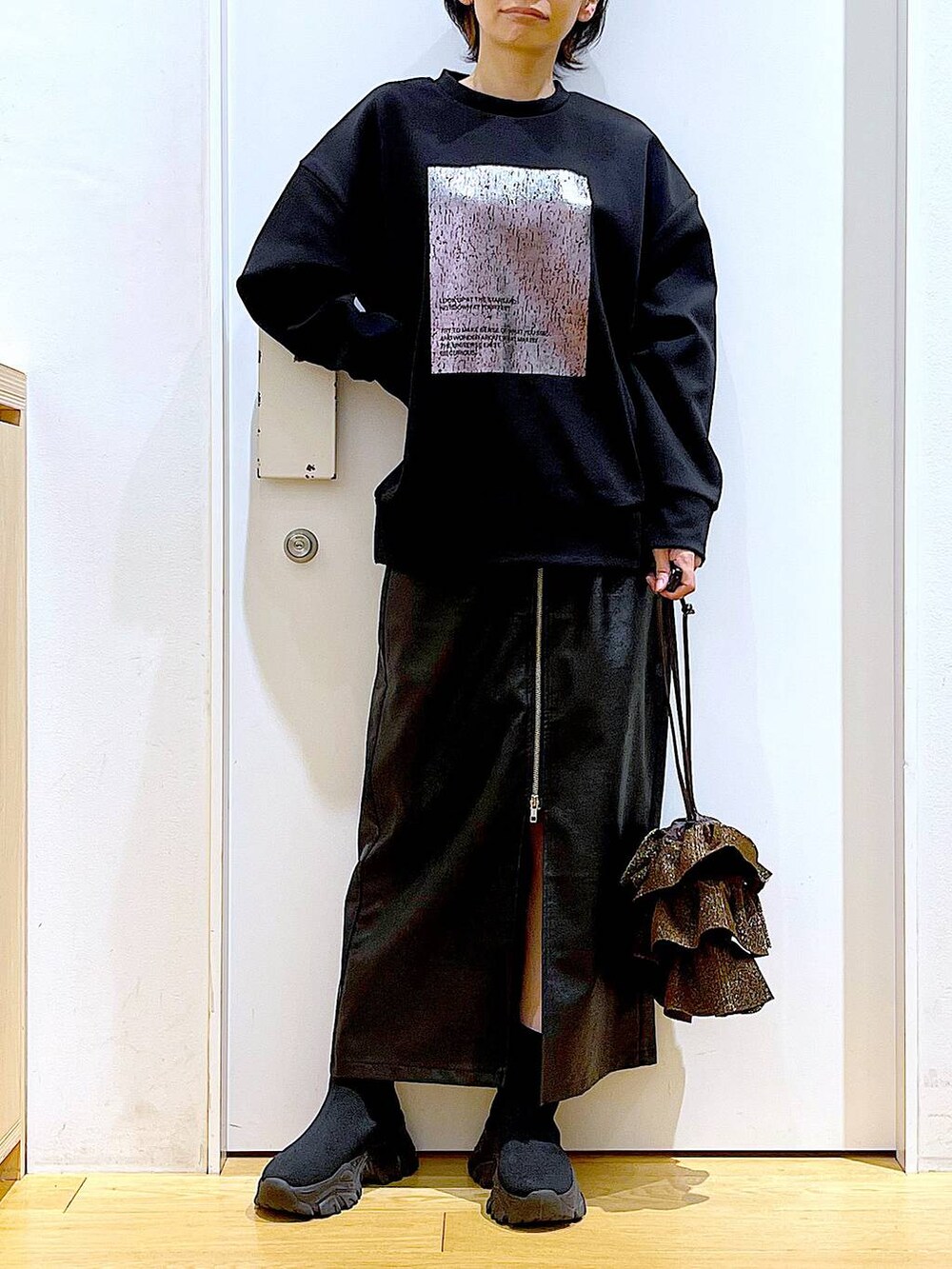 ブラック系のスカート、ブラック系のブーツ、ブラウン系のショルダーバッグを着用したレディースの冬コーディネートの6枚目の写真