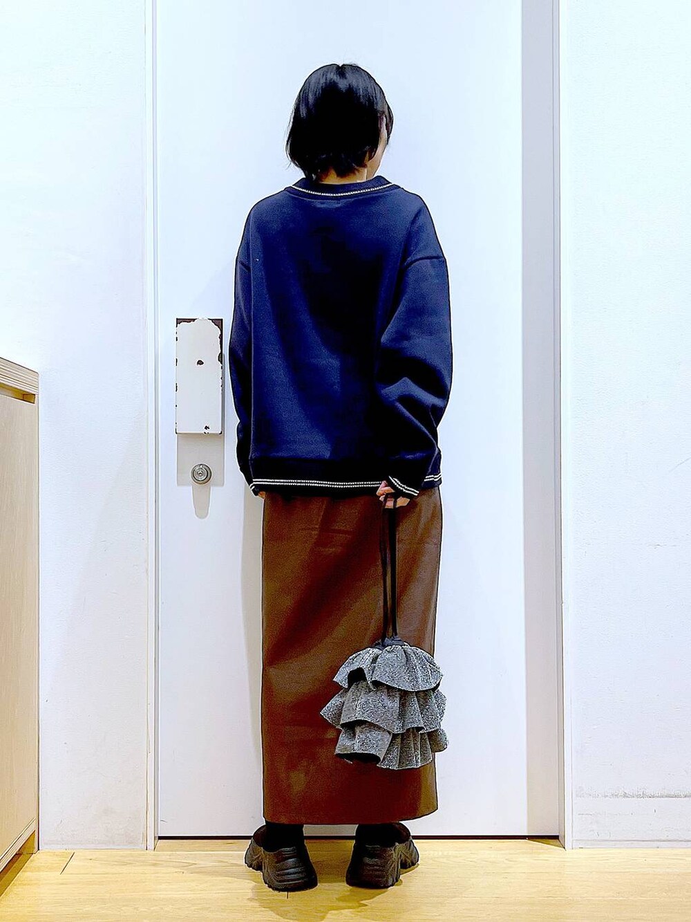 ブラウン系のスカート、ブラック系のブーツ、シルバー系のショルダーバッグを着用したレディースの冬コーディネートの5枚目の写真