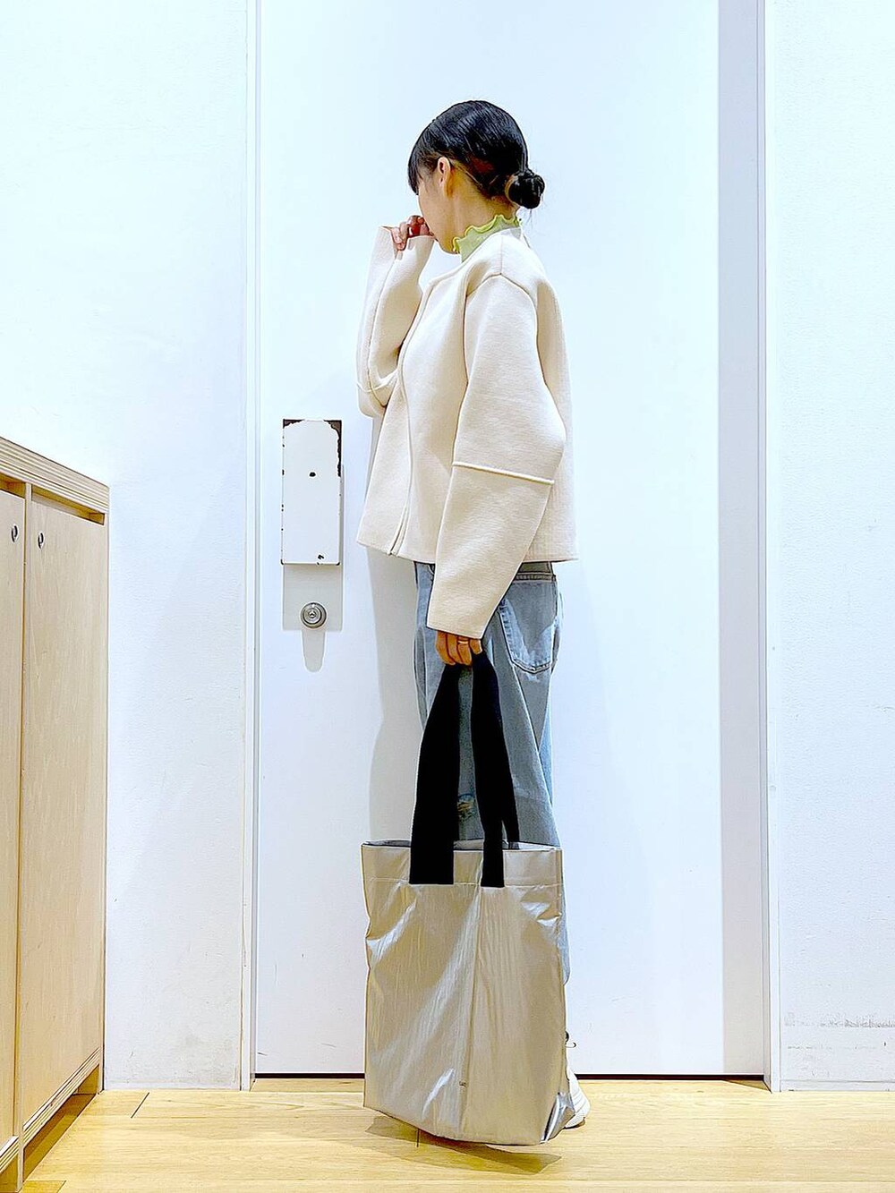 グリーン系のTシャツ/カットソー、ベージュ系のスニーカー、ブルー系のデニムパンツを着用したレディースの冬コーディネートの3枚目の写真