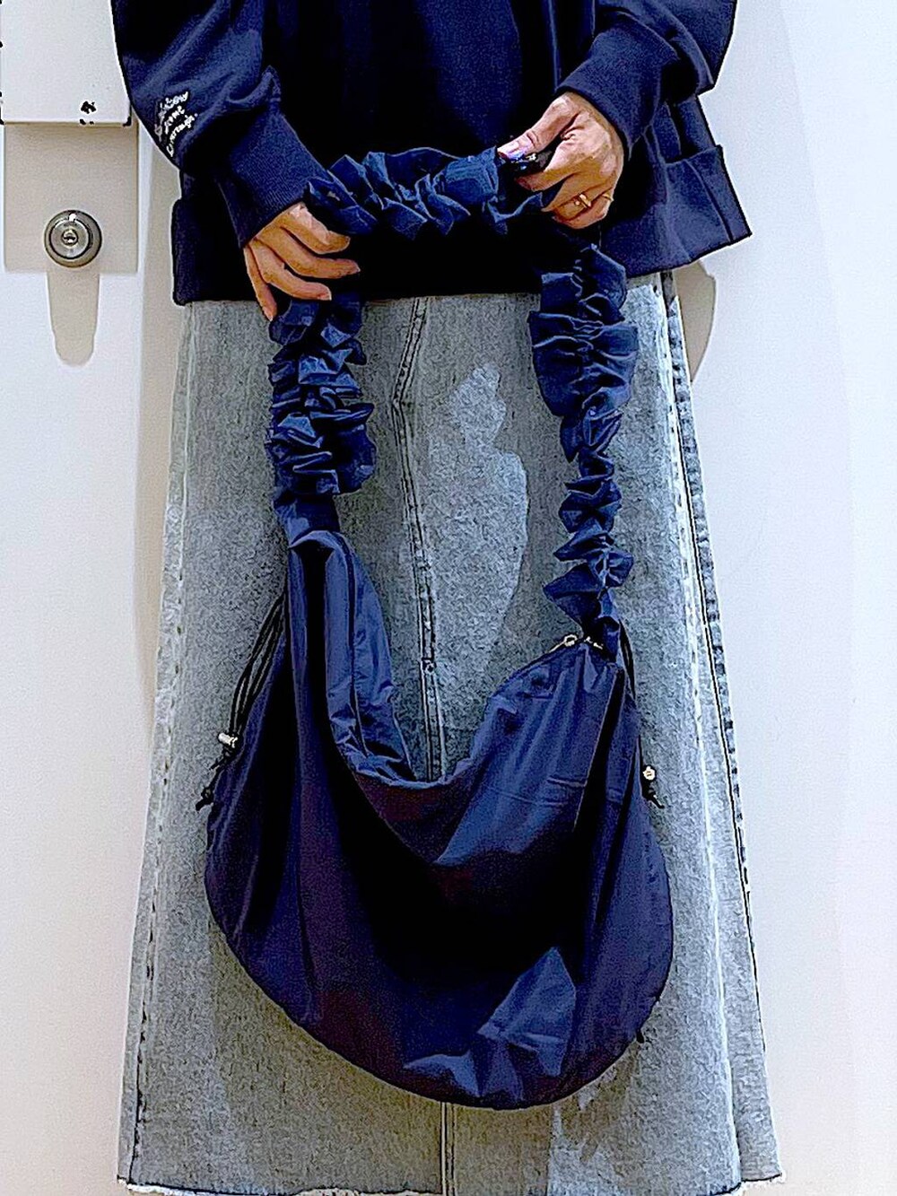 ブルー系のショルダーバッグ、ブラック系のブーツ、ブルー系のデニムスカートを着用したレディースの春コーディネートの9枚目の写真