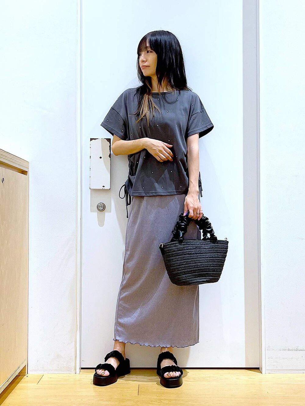 パープル系のスカート、ブラック系のショルダーバッグ、ブラック系のサンダルを着用したレディースの夏コーディネートの2枚目の写真