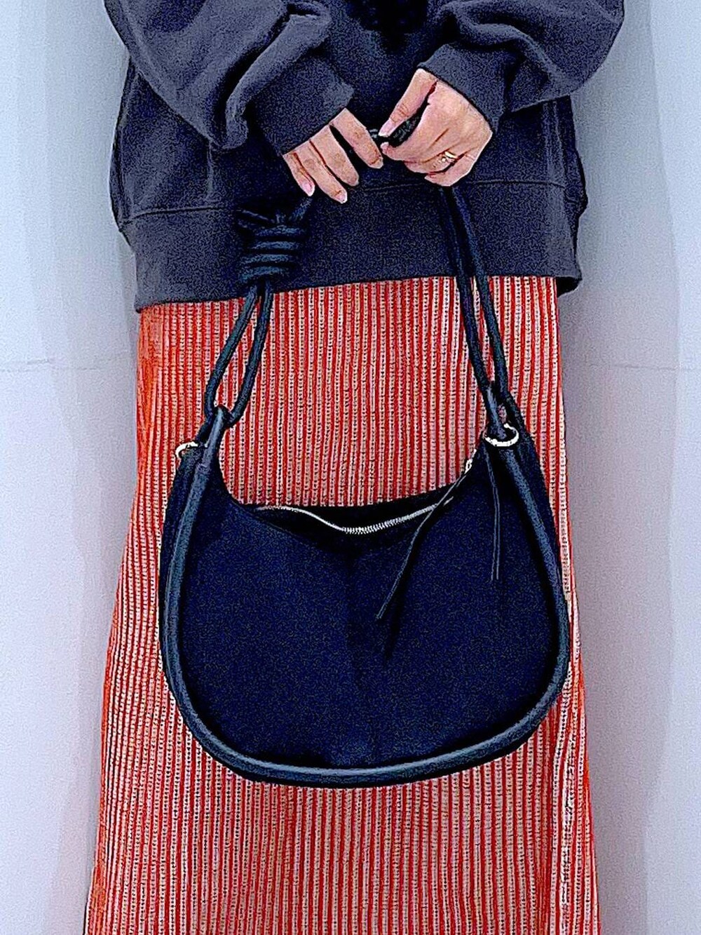 オレンジ系のスカート、ブラック系のブーツ、ブラック系のショルダーバッグを着用したレディースの秋コーディネートの9枚目の写真