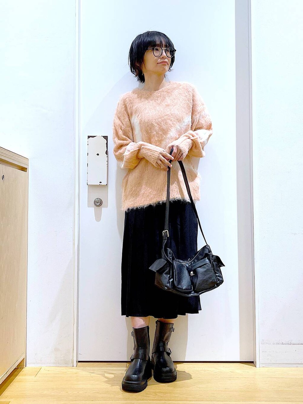 ピンク系のニット/セーター、ブラック系のブーツ、ブラック系のショルダーバッグを着用したレディースの秋コーディネートの2枚目の写真