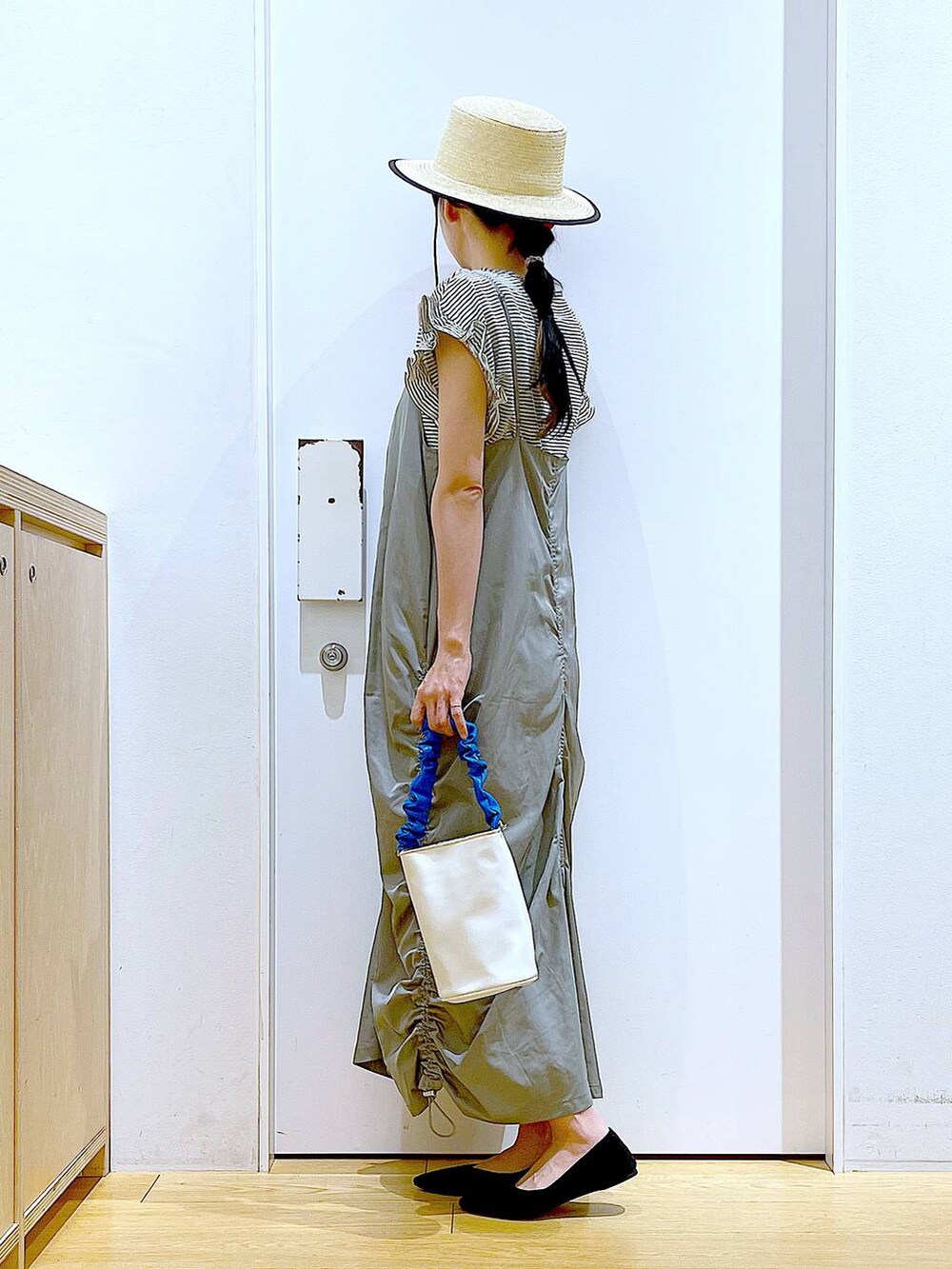 ブルー系のショルダーバッグ、ブラック系のパンプス、グリーン系のワンピースを着用したレディースの春コーディネートの3枚目の写真