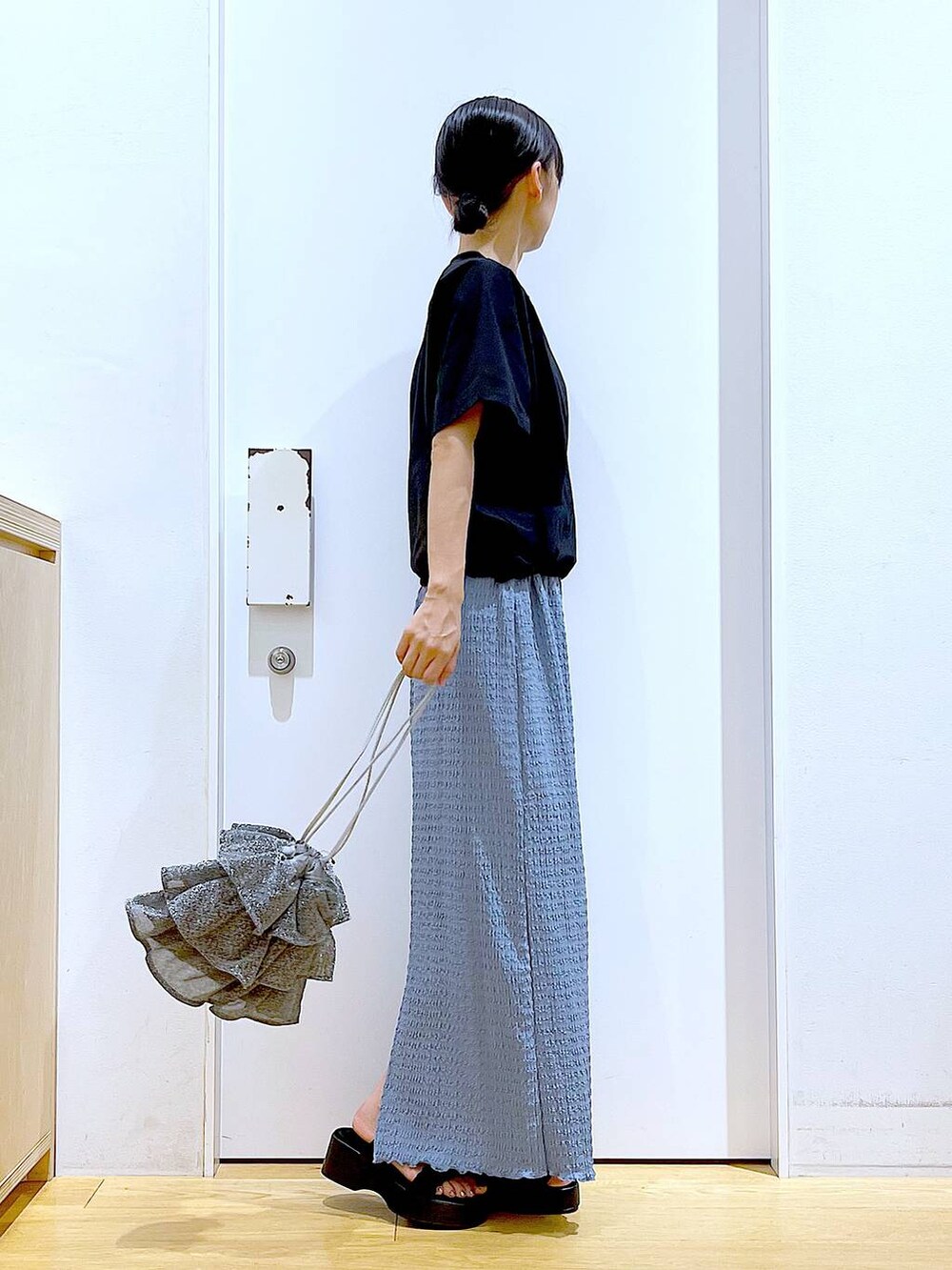 シルバー系のショルダーバッグ、ブルー系のスカート、ブラック系のTシャツ/カットソーを着用したレディースの夏コーディネートの4枚目の写真