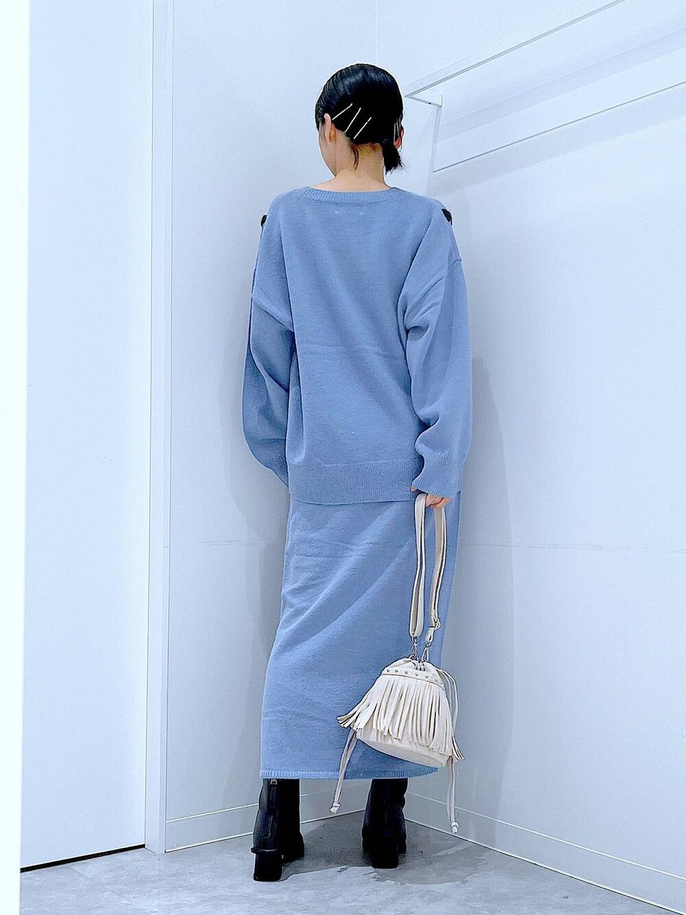 ブルー系のニット/セーター、ブルー系のスカート、ブラック系のブーツを着用したレディースの秋コーディネートの5枚目の写真